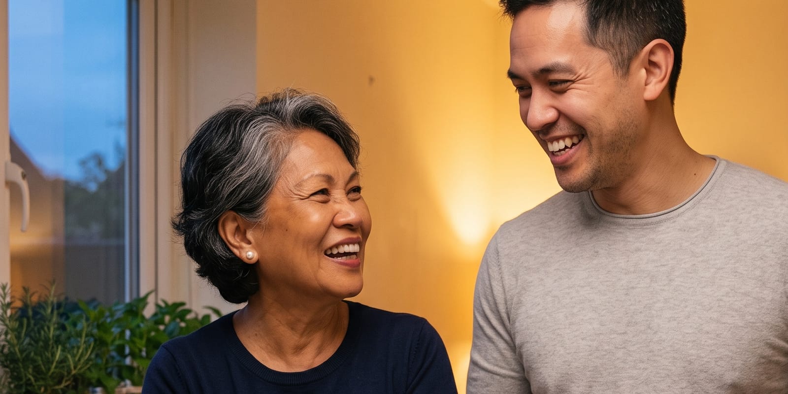 A mother and her grown son, laughing together at home.